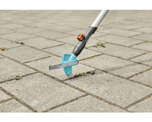 Gratte-joints en cours d''utilisation sur des pavés pour enlever les mauvaises herbes