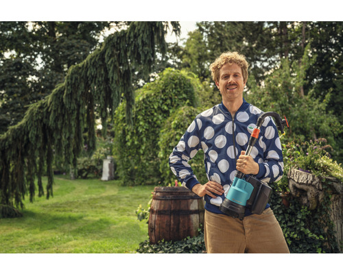 Mann im Garten mit einer Teichschlammsaugpumpe.