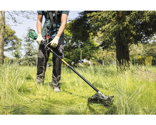 Eine Person benutzt einen Rasentrimmer, um Gras zu schneiden.