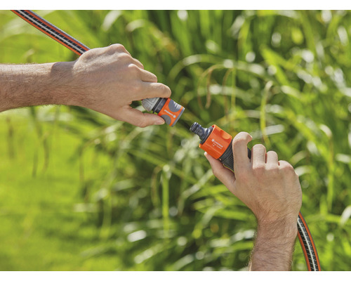 Deux mains raccordent un tuyau d''arrosage à un raccord de tuyau.