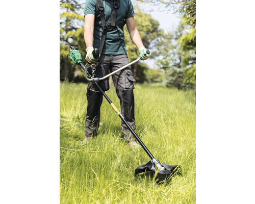 Eine Person benutzt einen Rasentrimmer, um Gras zu schneiden