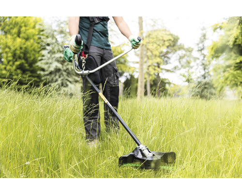 Eine Person benutzt einen Rasentrimmer auf einer Rasenfläche.