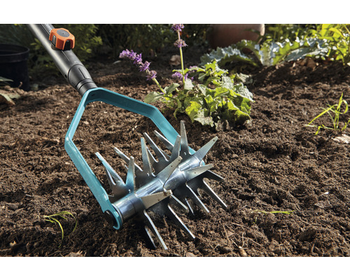 Scarificateur de jardin Gardena en utilisation dans la terre du jardin.