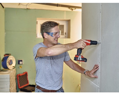 Mann schraubt Trockenbauwand mit Akku-Bohrschrauber