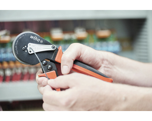 Une personne utilise une pince à sertir Wiha pour sertir un câble