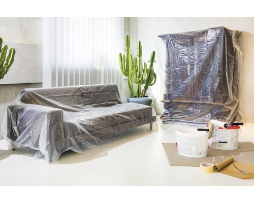 Wohnzimmer mit abgedecktem Sofa und Schrank als Vorbereitung für Renovierungsarbeiten