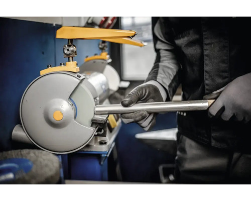 Eine Person schleift mit einer Doppelschleifmaschine ein Metallrohr.