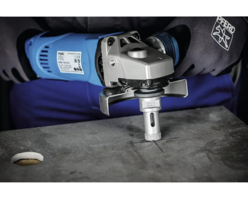 Eine Person bohrt mit einem Winkelschleifer und einem Diamantbohrer ein Loch in Stein.