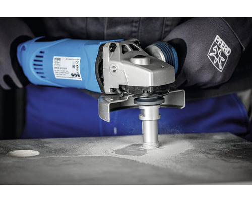 Person bohrt mit einer blauen Flex ein Loch in eine graue Platte, die mit PFERD-Handschuhen geschützt wird.