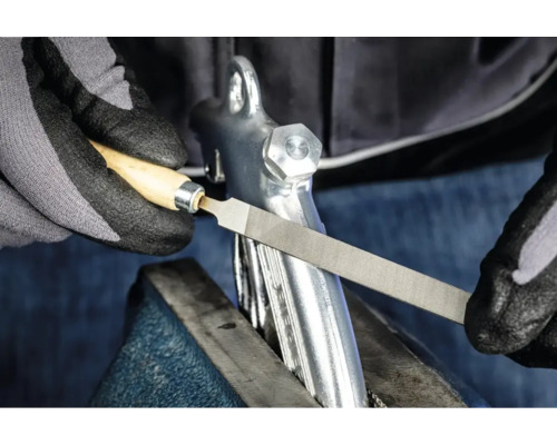 Une lime à métaux avec manche en bois utilisée pour travailler une pièce dans un étau.