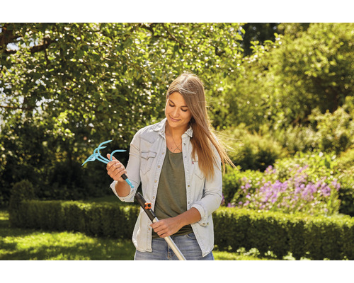 Femme tenant un accessoire de griffe de jardin avec manche dans un jardin