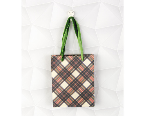 Einkaufstasche mit Karomuster und grünen Tragegriffen hängt an einem Haken.