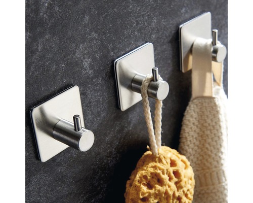 Drei selbstklebende Haken aus Edelstahl an einer Wand befestigt, mit einem Schwamm und einem Handtuch daran.