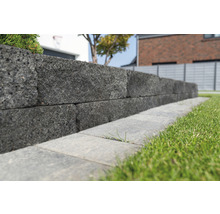 Un mur en pierres grises dans un jardin.