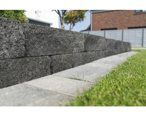 Eine Mauer aus grauen Steinen in einem Garten.