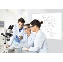 Scène dans un laboratoire avec trois scientifiques, un microscope et un tableau blanc avec des formules chimiques