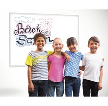 "Quatre enfants se tiennent devant un tableau avec l''inscription ""Retour à l''école""."