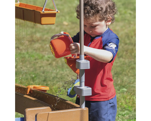 Kind spielt mit einer Wasserbahn im Garten