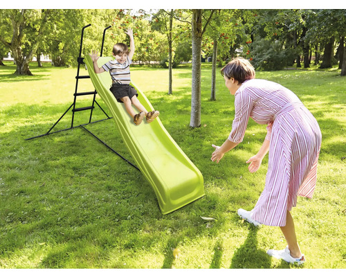 Garçon glissant sur un toboggan de jardin pendant qu''une femme l''attrape