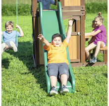 Kind rutscht auf Spielplatzrutsche, während andere Kinder schaukeln und auf der Bank sitzen