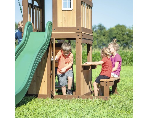 Holzspielhaus mit Rutsche und Tisch mit Bank im Garten