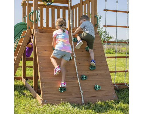 Deux enfants grimpent sur un mur d''escalade en bois avec des prises.