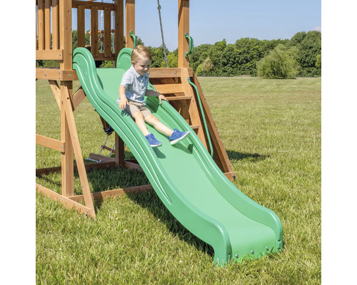 Garçon glissant sur un toboggan vert d''une tour de jeux dans le jardin