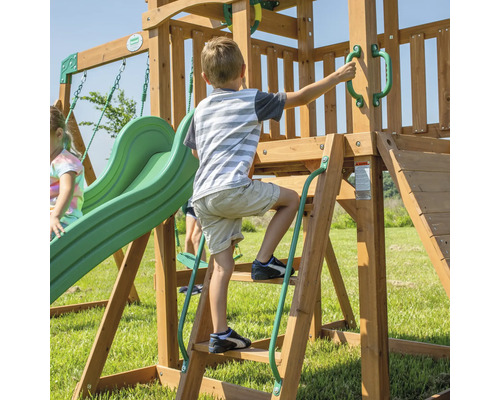Enfant grimpant sur une aire de jeux en bois avec toboggan et balançoire