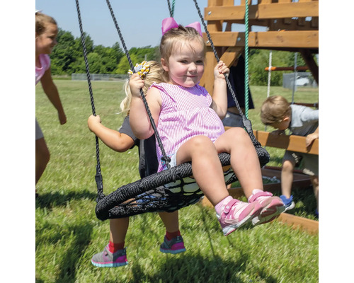 Des enfants se balancent sur une balançoire nid d''oiseau à l''extérieur