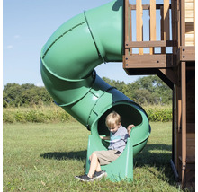 Junge auf einer grünen Röhrenrutsche auf einem Spielplatz