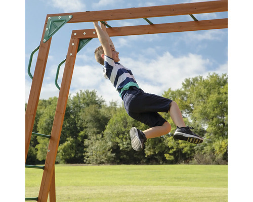 Un garçon s''accroche à une balançoire pour enfants dans le jardin.