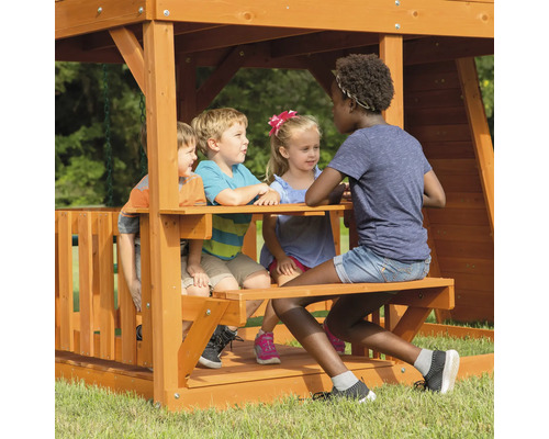 Des enfants jouent dans une aire de jeux en bois avec table de pique-nique.