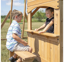 Kinder spielen an einem Spielturm aus Holz mit Fenster und Sitzbank