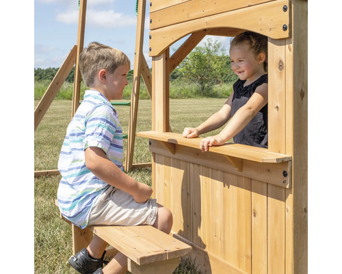 Des enfants jouent sur une tour de jeux en bois avec fenêtre et banc