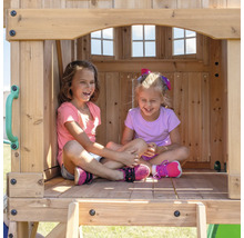 Zwei lachende Mädchen sitzen in einem Spielhaus aus Holz.
