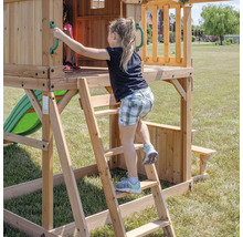 Mädchen klettert auf einem Holzspielturm mit Rutsche und Picknicktisch