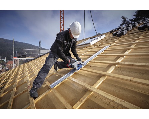 Ein Handwerker schneidet mit einer Handkreissäge ein Holzdach zu.