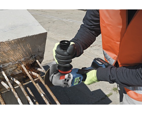 Une personne utilise une meuleuse d'angle sans fil pour couper des barres métalliques dans du béton.