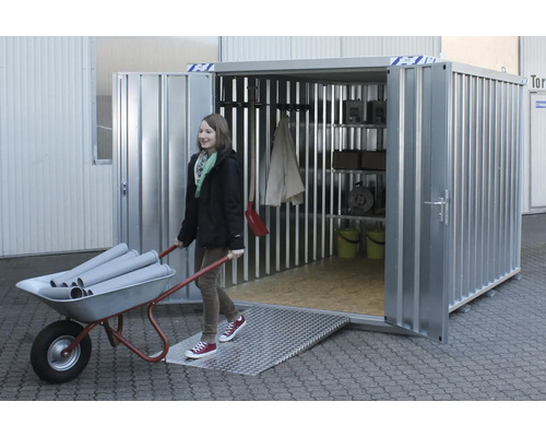 Conteneur en acier avec rampe et étagères. Une femme pousse une brouette remplie de tuyaux dans le conteneur.