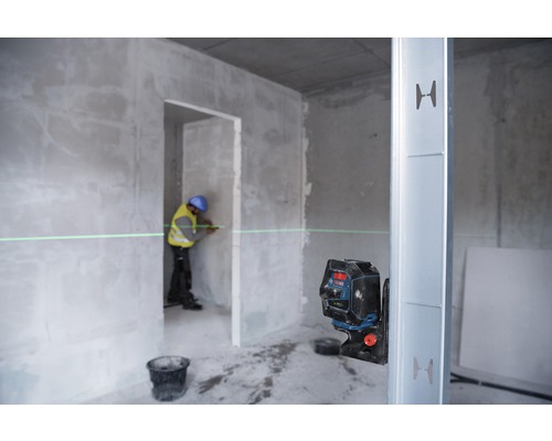 Un ouvrier utilise un laser de ligne dans un gros œuvre pour marquer une ligne droite sur un mur.