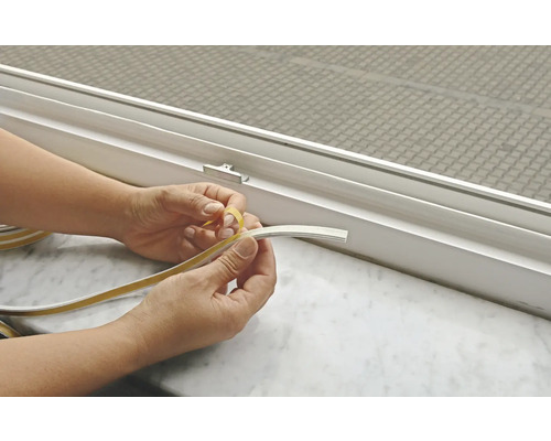 Person entfernt Schutzfolie von Fensterdichtband