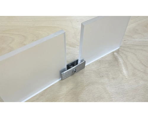 Deux plaques de verre acrylique reliées par un connecteur métallique sur une surface en bois
