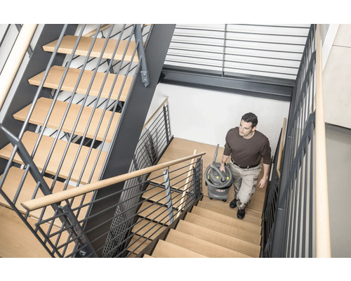 Mann trägt einen Mehrzwecksauger eine Treppe hinauf