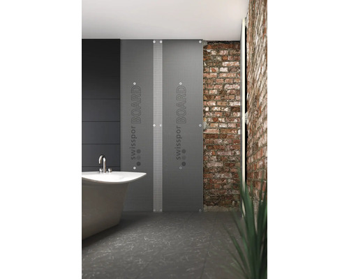 Salle de bains avec baignoire et panneaux d'isolation SwissPor Board devant un mur en briques