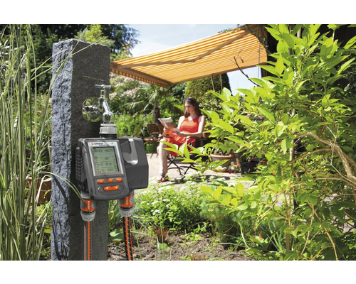 Gartenszene mit einem Gardena Bewässerungscomputer am Wasserhahn