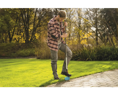 Un homme utilise un coupe-bordure dans le jardin pour travailler les bordures de pelouse
