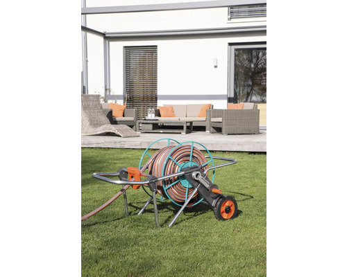 Gartenschlauchwagen auf Rasen vor Terrasse mit Gartenmöbeln