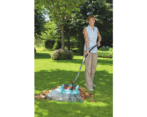 Femme ratissant les feuilles avec un râteau de jardin dans le jardin.