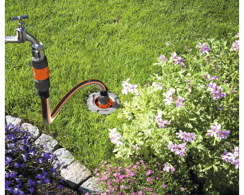 Wasserhahn verbunden mit einem unterirdischen Wasseranschluss im Garten.