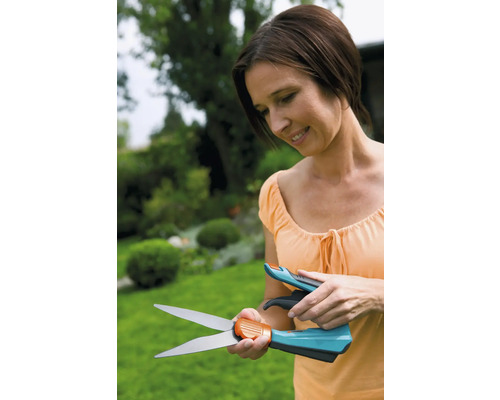 Femme examinant des cisailles à gazon sur fond de jardin